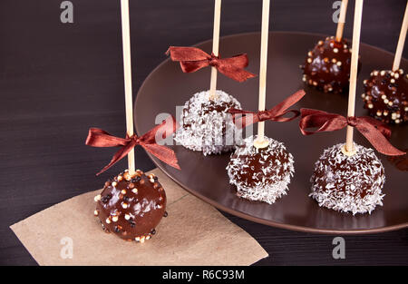 Verschiedene Kuchen Pops mit dunkler Schokolade auf einen hölzernen Tisch dekoriert Stockfoto