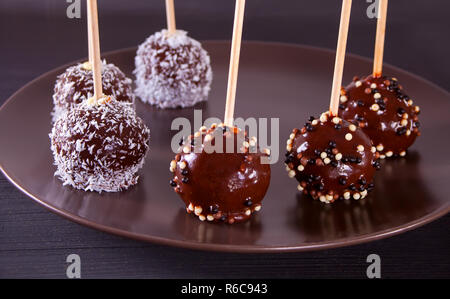 Verschiedene Kuchen Pops mit dunkler Schokolade auf einen hölzernen Tisch dekoriert Stockfoto