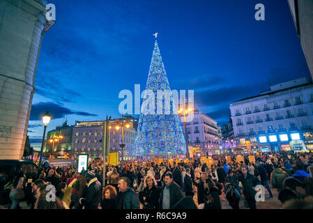 Puerta del Sol Platz bei Einbruch der Dunkelheit durch die Weihnachtsbeleuchtung und ein glänzender Weihnachtsbaum beleuchtet. Blick von der Calle de Carretas Straße. Stockfoto