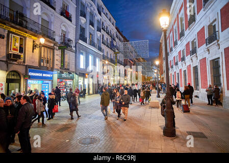 Menschen zu Fuß auf die Calle Carretas Straße bei Einbruch der Dunkelheit durch die Weihnachtsbeleuchtung illuminiert. Blick von der Puerta del Sol. Stockfoto