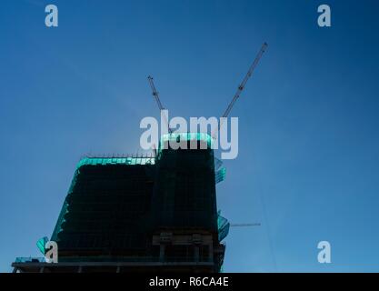 Krane in Betrieb über eine Baustelle mit blauem Himmel in Vietnam. Stockfoto