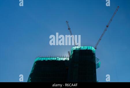 Krane in Betrieb über eine Baustelle mit blauem Himmel in Vietnam. Stockfoto