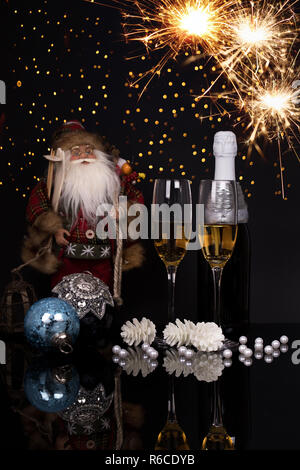 Zwei Weingläser mit Champagner, Santa Claus, Wunderkerzen und Weihnachten Ornamente auf einem schwarzen Hintergrund mit Reflexion. Kopieren Sie Platz. Frohe Weihnachten und Stockfoto
