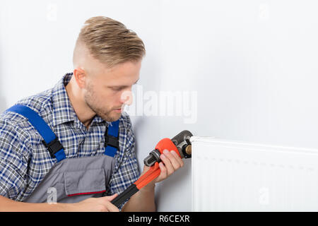 Männliche Klempner zur Festsetzung Thermostat mit einem Schraubenschlüssel Stockfoto