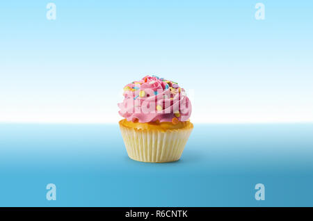 Cupcake mit Zuckerguss und bunten Bonbons auf eine blaue Fläche Stockfoto