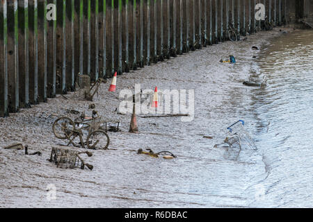 Einkaufswagen, Fahrräder und andere Objekte in einem Tidal River geworfen werden von Schlamm und Schlick bedeckt, das littering und Umwelt Schaden Stockfoto