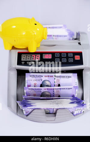 Indische Banknoten hundert Rupien an die Währung Zähler Maschine mit Sparschwein. Auf den weißen Hintergrund isoliert. Stockfoto
