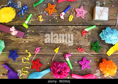 Pfeifen, Ballons, Geschenke, Kerzen, Dekoration auf alten hölzernen Hintergrund. Konzept der Kindergeburtstag. Ansicht von oben. Flach. Stockfoto