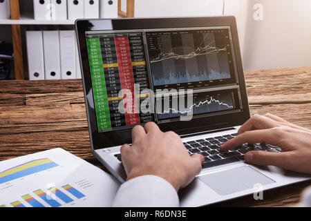 Börse Broker mit Blick auf Diagramme auf Laptop Stockfoto