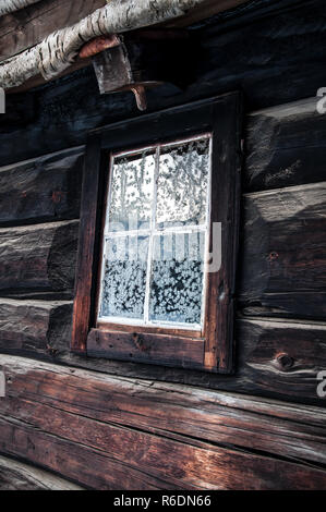 Rustikales haus mit Schneeflocken am Fenster Stockfoto