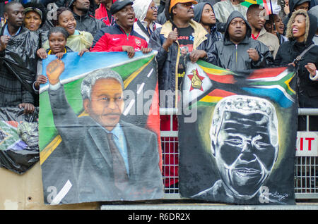 Trauernde tragen Banner und Bilder des ehemaligen Präsidenten Nelson Mandela, affectionaly genannt Madiba, an der Trauerfeier für den ehemaligen südafrikanischen Präsidenten am FNB-Stadion, in Soweto, Dienstag, 10. Dezember 2013. Mandela starb am 5. Dezember 2013. Foto: EVA-LOTTA JANSSON Stockfoto