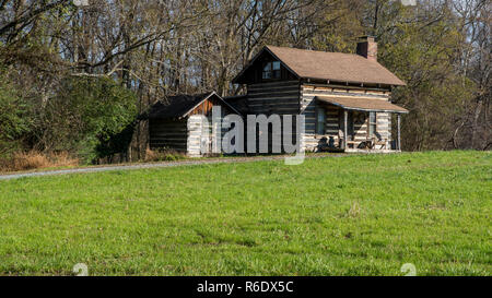 Alte Kabine im Feld neben Holz mit Schuppen/Outhouse daneben Stockfoto