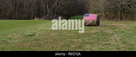 Amerikanische Flagge auf dem Ballen Heu mit Hand vor Pflug Stockfoto