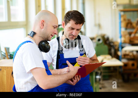 Zwei Arbeiter in einer Schreinerei im Gespräch Stockfoto