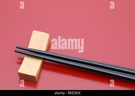 Essstäbchen und Stäbchen - Rest auf einem roten Hintergrund Fach Stockfoto