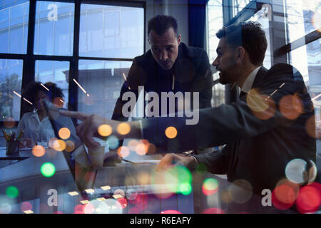 Geschäftsleute arbeiten zusammen im Büro mit einem Laptop. Konzept der Teamarbeit und Partnerschaft. Double Exposure Stockfoto