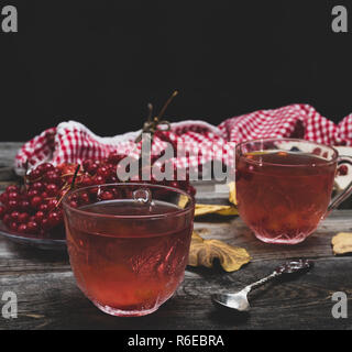 Frischem heißem Kaffee von viburnum Beeren in eine transparente Schale auf einem grauen Hintergrund Holz Stockfoto