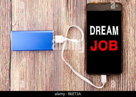 Wort, Schrift, Traumjob. Business Konzept für Träumen über Beschäftigung Job Position auf mobile Handy Mobile und macht geschrieben-bank Ladegerät auf alten Holz Hintergrund Stockfoto