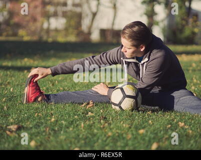 Fußballspieler, die sich mit Fußball im Park an einem sonnigen Herbsttag Stockfoto