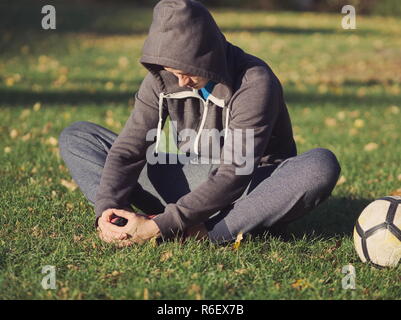 Fußballspieler, die sich mit Fußball im Park an einem sonnigen Herbsttag Stockfoto