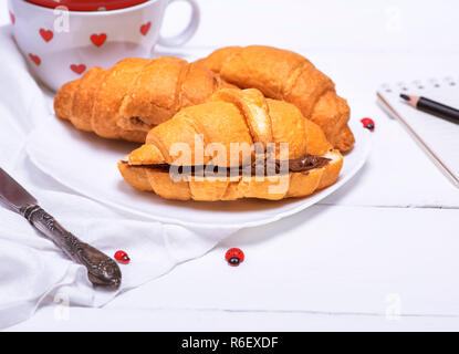 Gebackene Croissants mit Schokolade auf einem weißen Teller Stockfoto