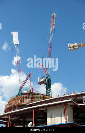 Turmkrane auf industriellen Hochbau über blauen Himmel mit hellen Wolken vertikale Ansicht Stockfoto