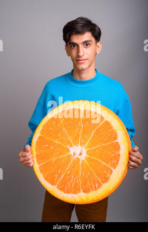 Junge persische Teenager halten großes Stück orange Frucht Stockfoto