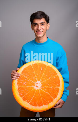 Junge persische Teenager halten großes Stück orange Frucht Stockfoto