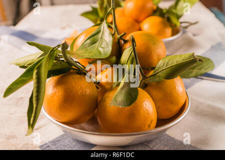 Flach auf reife Orangen Mandarinen oder Mandarinen Obst mit grünen Blättern, über rustikale Hintergrund, senkrecht. Stockfoto