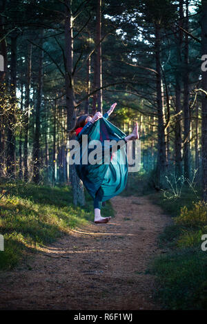 Schöne, junge Frau levitierten in Wäldern. Fliegen im Traum. Das Fehlen der Schwerkraft. Konzept der Magie, Wunderland und Märchen im Wald. Stockfoto