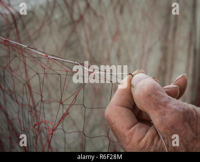 Hand einer alten Fischer mit der Instandsetzung des Net für die Fischerei Stockfoto