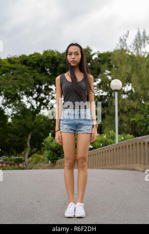 Die volle Länge der junge schöne asiatische Frau Entspannung im Park Stockfoto