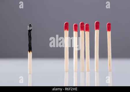 Verbrannt Streichholz getrennt durch rote Streichhölzer Stockfoto