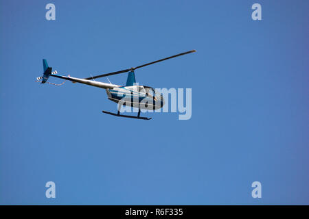 Leichter Hubschrauber gegen blie Himmel, mit Rotoren im Moment an einem hellen, sonnigen Tag gefroren Stockfoto