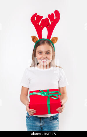 Kind in deer Hörner mit Geschenk Box in der Hand auf weißem Hintergrund. Weihnachten Konzept. Stockfoto