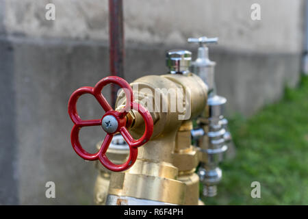 Wasseranschluss mit einem roten Rad in der vor einem Haus an der Wand Stockfoto