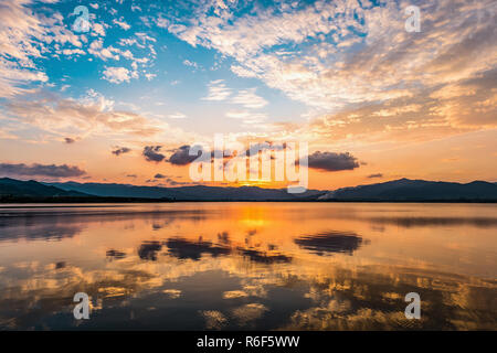 Panoramablick auf dramatische bewölkter Sonnenuntergang Himmel reflektieren Ruhe flache Wasserfläche des Sees im tropischen Wald von Prachuap Khiri Khan, Thailand. Stockfoto