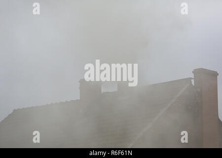 Rauch aus dem Schornstein eines Hauses getankt mit Kohle Stockfoto