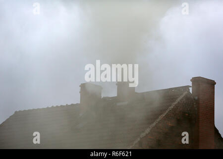 Rauch aus dem Schornstein eines Hauses getankt mit Kohle Stockfoto