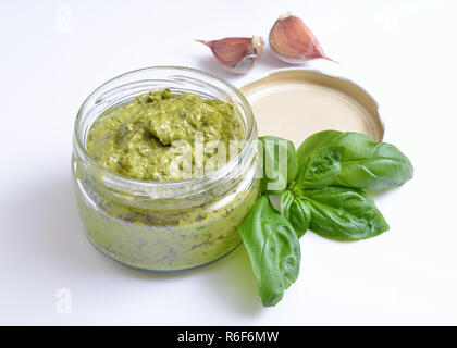 Pesto in einem Glas mit Basilikum und Knoblauch. Auf weiß. Stockfoto
