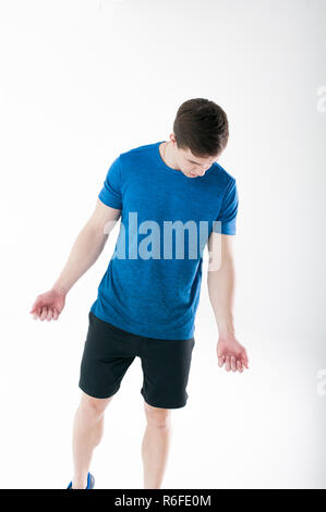 Junge muskulöse schönen athletischen Mann in Blau Sport Shirt, Shorts und Turnschuhen stehen auf weißen Hintergrund im Studio gekleidet Stockfoto