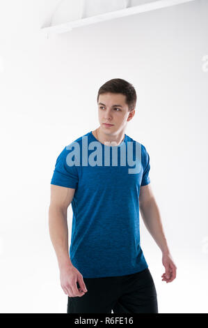 Junge muskulöse schönen athletischen Mann in Blau Sport Shirt, Shorts und Turnschuhen stehen auf weißen Hintergrund im Studio gekleidet Stockfoto