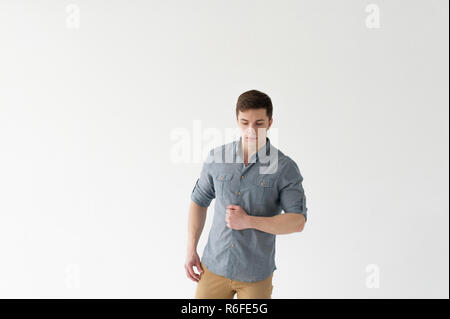 Jungen gutaussehenden Mann starken athletische bauen, in Hemd und braune Hose gekleidet, posiert auf weißem Studiohintergrund Stockfoto