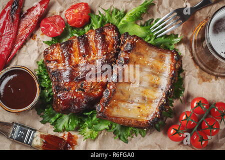 Nahaufnahme von Rippchen vom Grill mit BBQ Sauce und karamellisierten in Honig auf ein Papier. Leckeren Snack zum Bier. Ansicht von oben. Flach Stockfoto