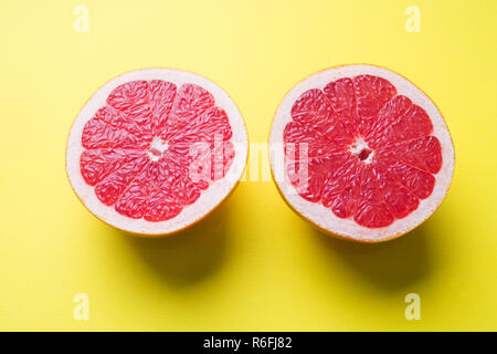 Die beiden Hälften der Grapefruit Schnitt längs auf gelbem Hintergrund Stockfoto