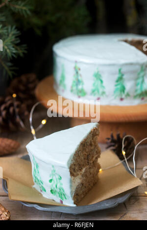 Festliche Kuchen mit gemalten Weihnachtsbaum auf einem dunklen Hintergrund der Zweige und Zapfen dekoriert. Im rustikalen Stil. Stockfoto