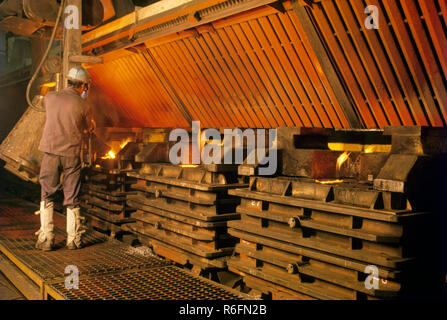 Arbeiter gießt geschmolzenes Gelb in Formen aus Stahl Stockfoto