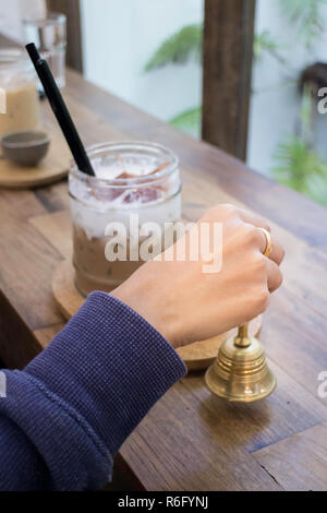 Hand auf Messing Glocke in Coffee Shop Stockfoto