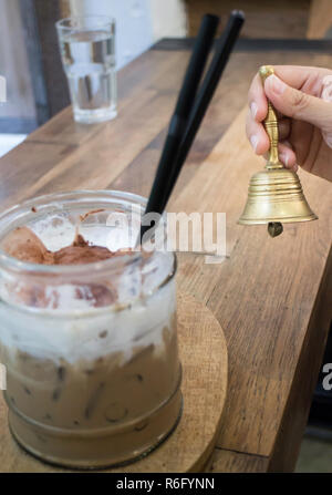 Hand auf Messing Glocke in Coffee Shop Stockfoto