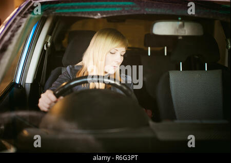 Porträt blonde Frau sitzt hinter Rad im Fahrersitz blaues Auto. Hände am Lenker, Probleme der weiblichen fahren Stockfoto